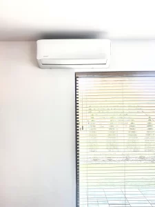 Biały klimatyzator ścienny Rotenso Imoto zamontowany nad oknem